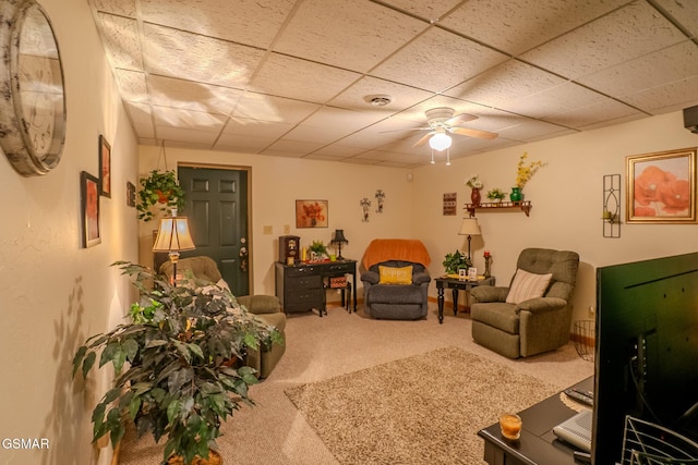 carpeted living room featuring ceiling fan and a drop ceiling