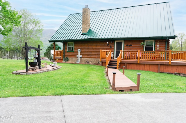 view of front of property with log exterior, a chimney, a standing seam roof, a front lawn, and metal roof