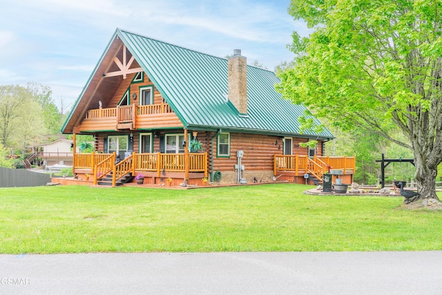 back of house featuring log exterior, a standing seam roof, a porch, a chimney, and a lawn