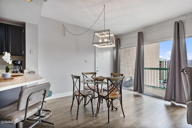 dining space with a textured ceiling, baseboards, and wood finished floors