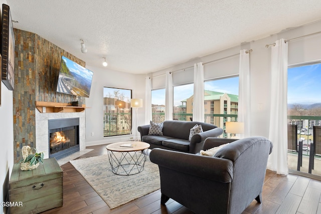 living room with a textured ceiling, wood finished floors, and a tile fireplace