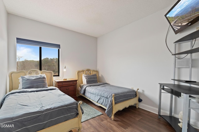 bedroom with a textured ceiling, wood finished floors, and baseboards