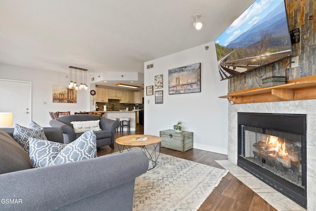 living room featuring dark wood-type flooring, a fireplace with flush hearth, and baseboards