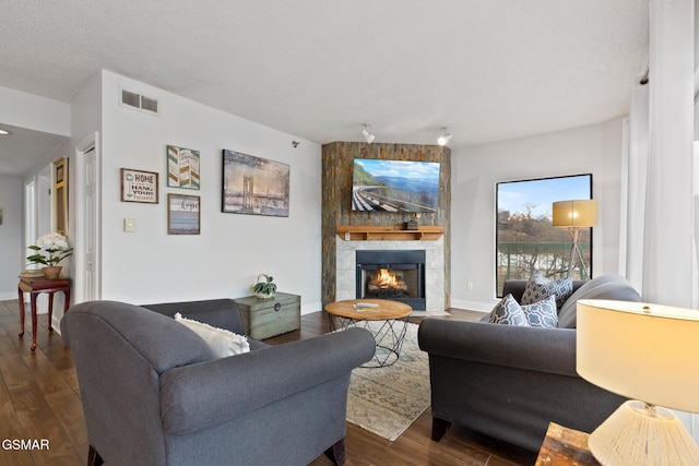 living room with dark wood-style floors, a fireplace, visible vents, and baseboards