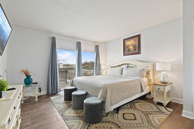 bedroom featuring a textured ceiling, baseboards, and wood finished floors