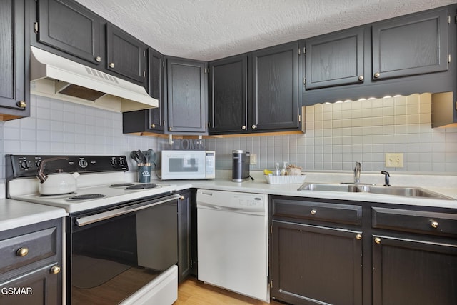 kitchen featuring light countertops, white appliances, a sink, and under cabinet range hood