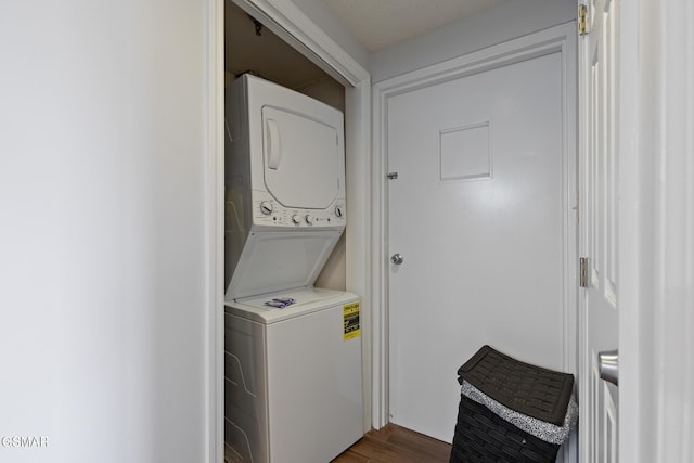 laundry area featuring stacked washing maching and dryer, dark wood-style floors, and laundry area