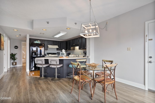 dining room featuring light wood finished floors, baseboards, a chandelier, and recessed lighting