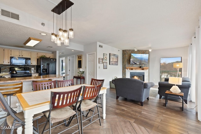 dining space featuring light wood finished floors, a fireplace, and visible vents