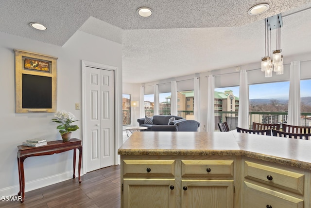 kitchen with baseboards, open floor plan, light countertops, dark wood finished floors, and decorative light fixtures