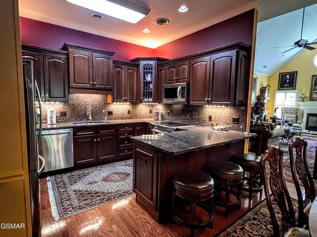 1042 Fine Glen Dr, Sevierville, TN 37862 - kitchen with appliances with stainless steel finishes, a kitchen bar, light wood-type flooring, dark brown cabinetry, and glass insert cabinets