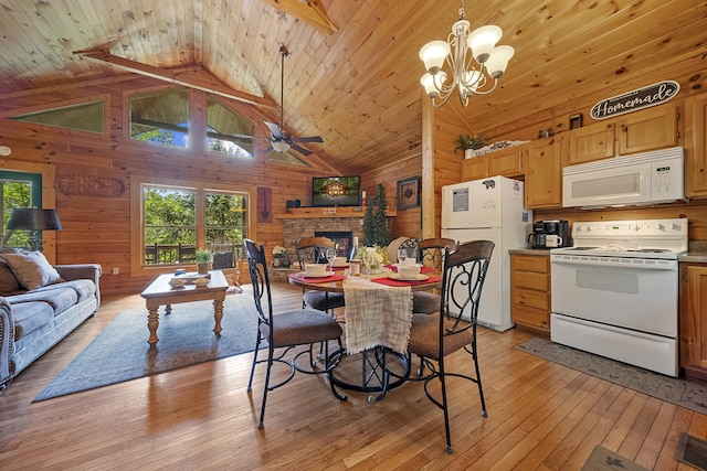 dining space with wood walls, wooden ceiling, high vaulted ceiling, a fireplace, and light hardwood / wood-style floors