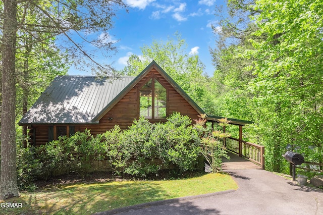 view of property exterior with log siding, a yard, metal roof, and aphalt driveway