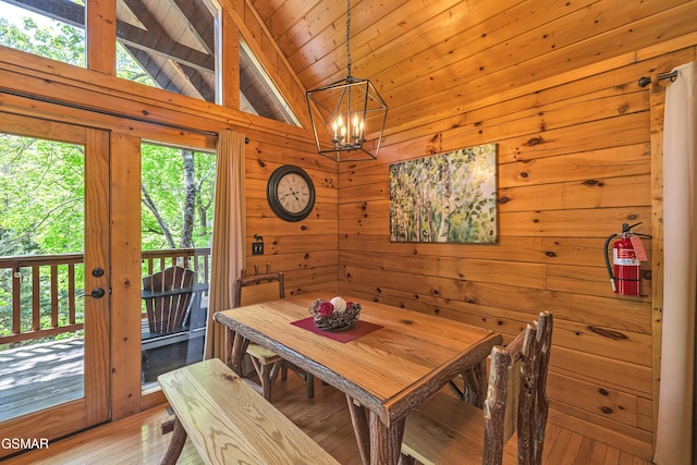 dining area featuring an inviting chandelier, wood walls, light wood-type flooring, wooden ceiling, and lofted ceiling with beams