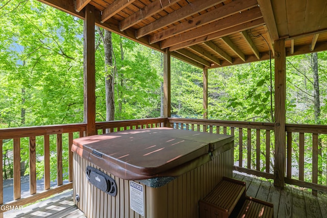 wooden deck featuring a hot tub and a forest view