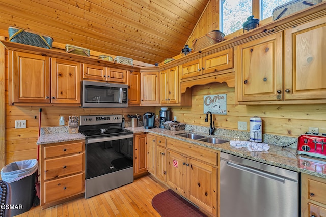 kitchen with wood ceiling, light stone countertops, a sink, wooden walls, and stainless steel appliances