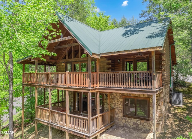 back of house featuring log exterior, metal roof, stone siding, and a deck