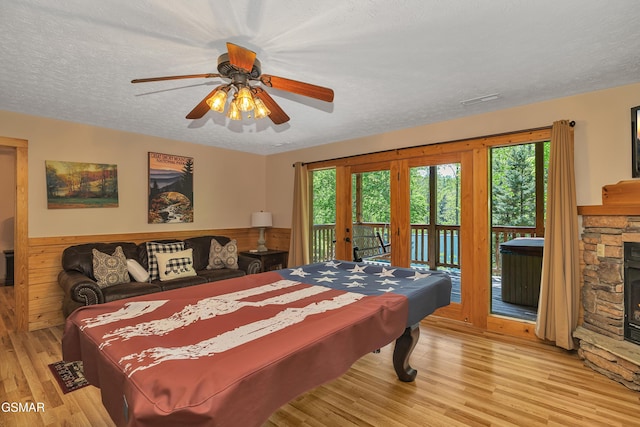 bedroom featuring access to outside, a textured ceiling, light wood-style floors, and multiple windows