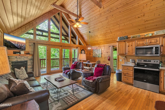 living room featuring wooden walls, high vaulted ceiling, wood ceiling, and a stone fireplace