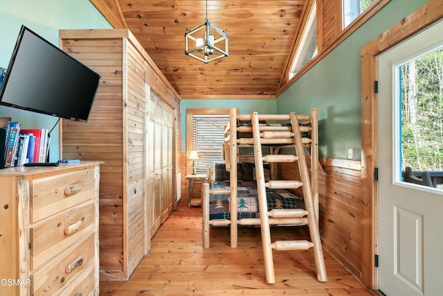 bedroom featuring light wood-style flooring, wood walls, wood ceiling, vaulted ceiling, and an inviting chandelier