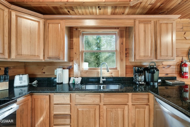 kitchen with wooden ceiling, wooden walls, a sink, light brown cabinetry, and dark stone countertops