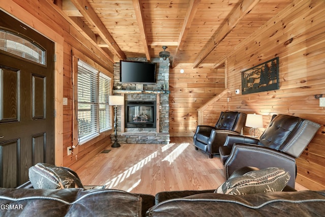 living room featuring wooden walls, wooden ceiling, a stone fireplace, and beam ceiling