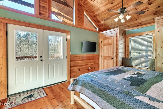 bedroom with vaulted ceiling, multiple windows, wood walls, and wooden ceiling