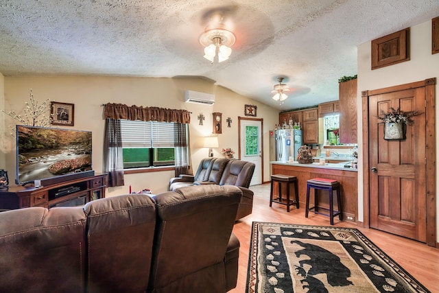2655 Craig Circle Way, Cosby, TN 37722 - living area featuring a wall unit AC, vaulted ceiling, light wood-type flooring, plenty of natural light, and a textured ceiling