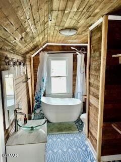 bathroom with a bathing tub, wood ceiling, and vaulted ceiling