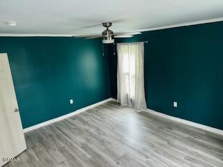 empty room with ceiling fan, hardwood / wood-style floors, and ornamental molding