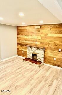 unfurnished living room featuring a stone fireplace, wood walls, and hardwood / wood-style floors