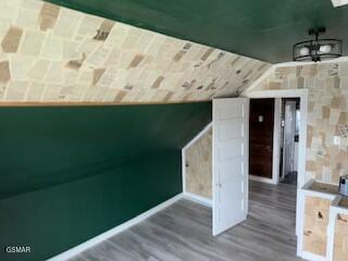 additional living space featuring wood-type flooring and vaulted ceiling