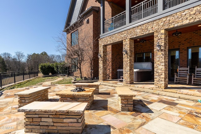 view of patio / terrace with a balcony, a fire pit, and fence