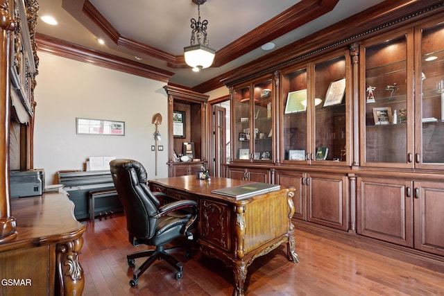 office space featuring a raised ceiling, light wood-style floors, and crown molding