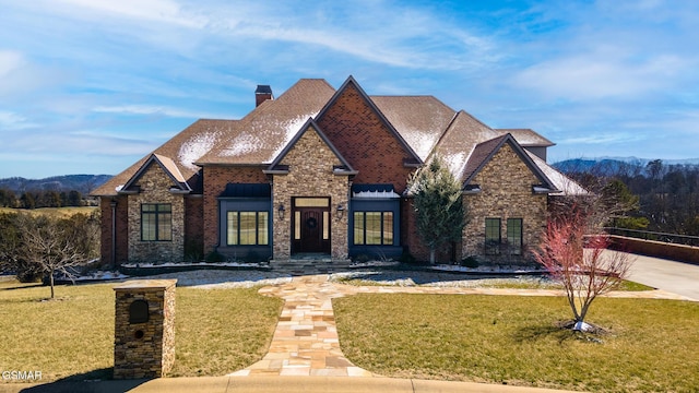 view of front of house featuring brick siding, a chimney, and a front yard