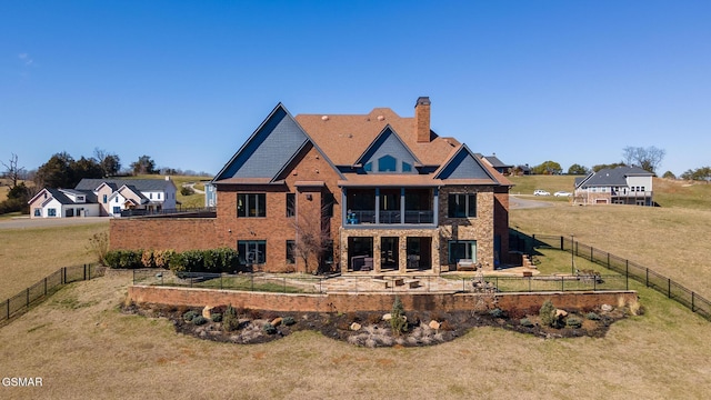 rear view of house with a balcony, a garden, a yard, a fenced backyard, and a chimney