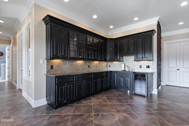 kitchen featuring a sink, dark stone counters, dark cabinetry, and beverage cooler