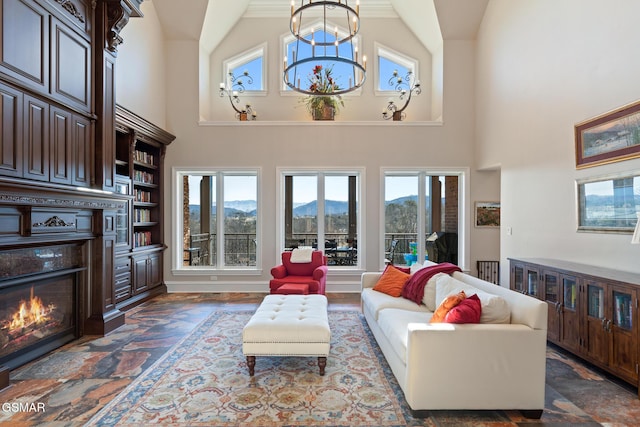 living room featuring a mountain view, high vaulted ceiling, a warm lit fireplace, and a chandelier