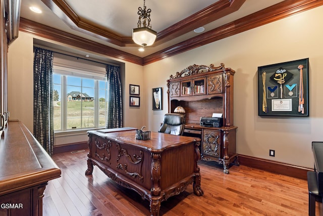 office area featuring visible vents, baseboards, a tray ceiling, ornamental molding, and wood finished floors