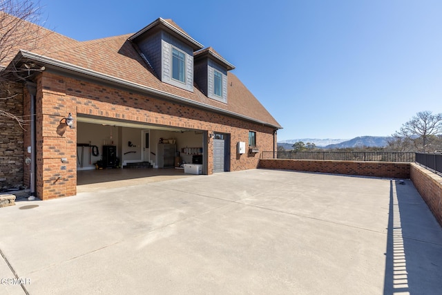 view of property exterior featuring brick siding, concrete driveway, a garage, and fence