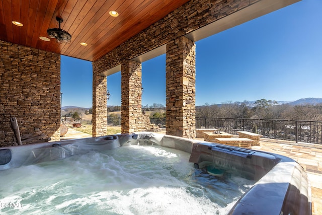 view of pool with a mountain view and a hot tub