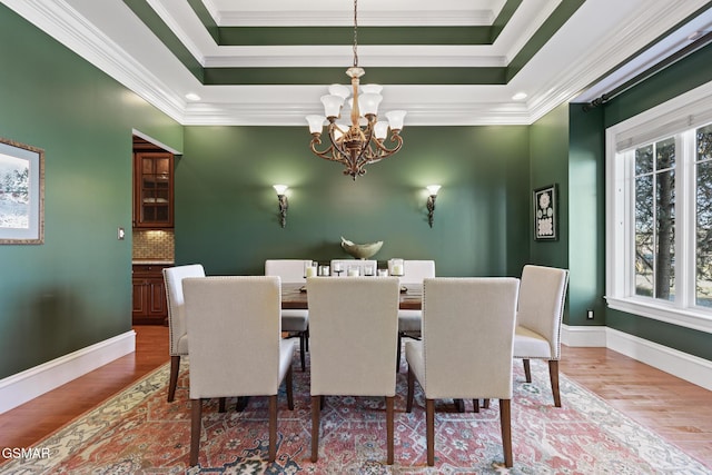 dining area featuring a raised ceiling, a healthy amount of sunlight, and a chandelier