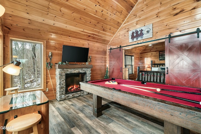 recreation room featuring a barn door, vaulted ceiling, wood walls, and pool table