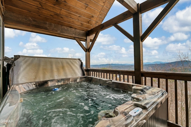 deck with a mountain view and a hot tub