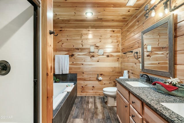 bathroom with tiled bath, vanity, wooden walls, hardwood / wood-style flooring, and wood ceiling