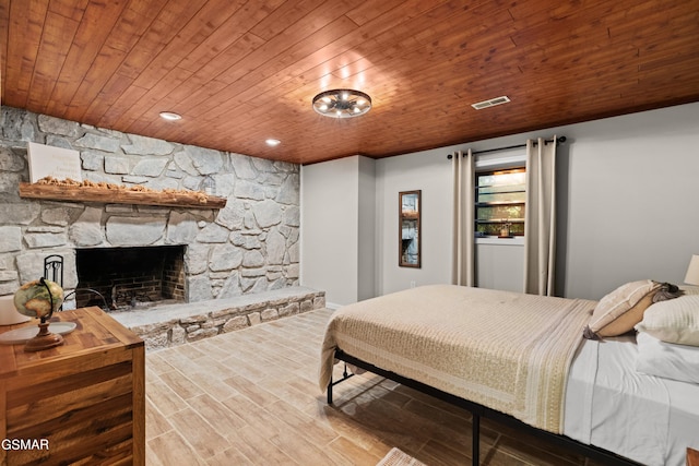 bedroom featuring a fireplace, hardwood / wood-style floors, and wood ceiling