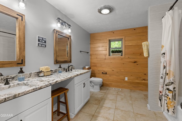 bathroom featuring vanity, toilet, and wood walls