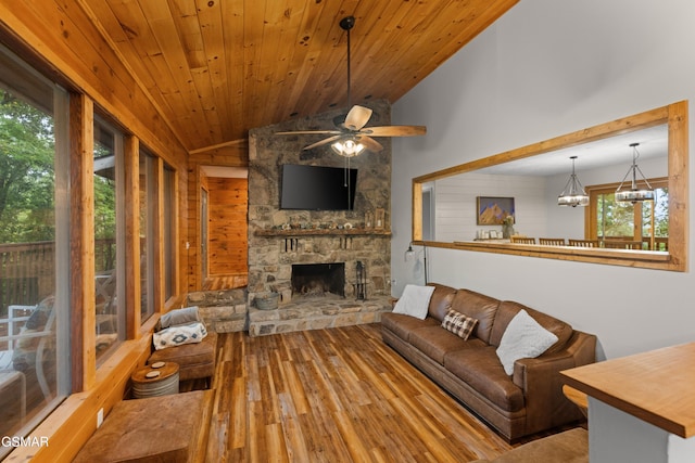 unfurnished living room with plenty of natural light, a stone fireplace, lofted ceiling, and ceiling fan with notable chandelier