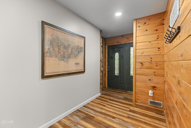 foyer entrance featuring wood-type flooring and wooden walls