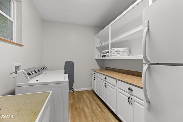 laundry area featuring cabinets, light wood-type flooring, and washing machine and dryer